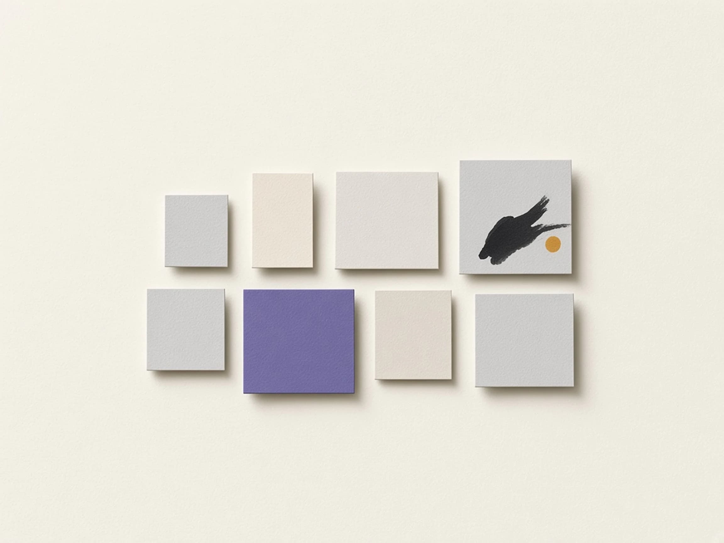 Grey and ivory paper swatches, one in violet and one marked with ink and an ochre dot